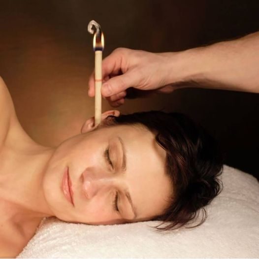 Ear Candling Treatment Woman relaxing with ear candling treatment being administered by a hand.