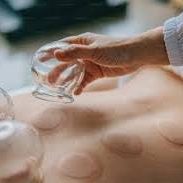 Hand placing a glass cup on a person's back for cupping therapy in a comfortable massage environment.
