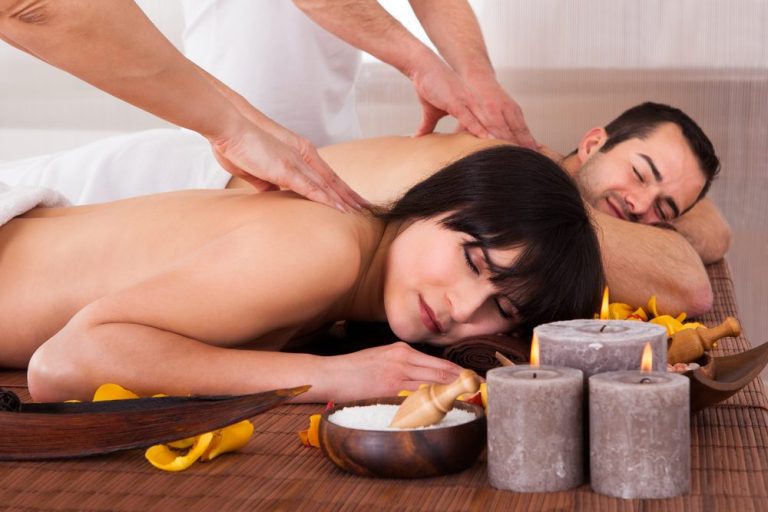 Couples Massage Treatment A couple receiving massages in a serene spa setting, surrounded by candles.