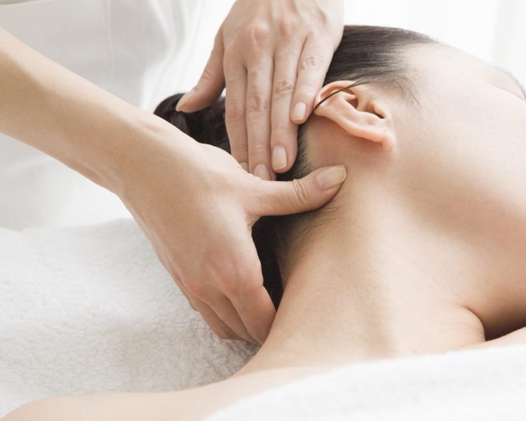 Woman Receiving Acupressure Massage Treanment A person receiving a neck massage with hands gently applying pressure.
